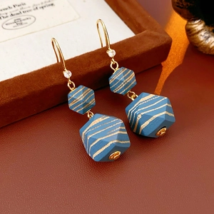Detailed view of blue hexagonal beads and gold hooks with zircons on leather