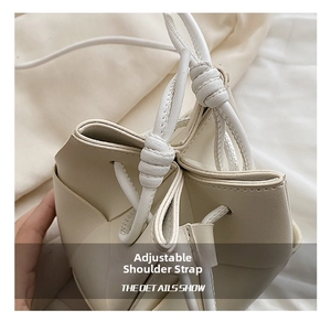 Detail showing the adjustable knotted strap and premium texture of the cream bucket bag