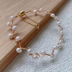 Macro detail of handmade freshwater pearl wire-wrapped bracelet with gold adjustable chain