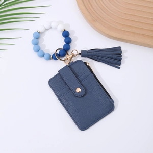 Detail of blue lychee leather card holder with silicone beaded bracelet and tassel charm