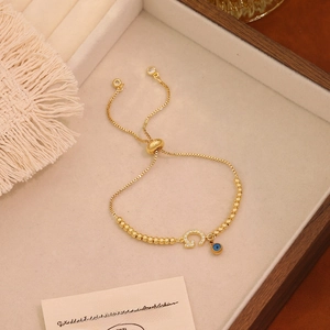 Dettaglio del bracciale regolabile in perline d'oro con ferro di cavallo e occhio blu