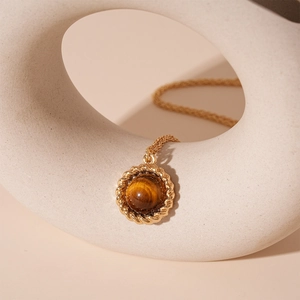 Artistic display of gold vintage round tiger eye stone pendant necklace on ceramic stand