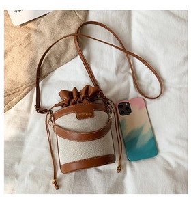 Detail view of contrast bucket bag showing drawstring closure and brown PU leather trim