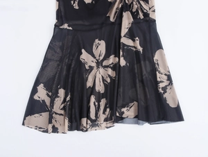 Détail d'une robe en maille noire avec fleurs bicolores et ourlet plissé en coupe A