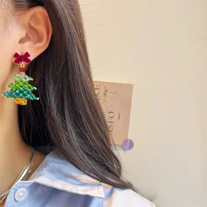 Detail of model wearing handmade beaded Christmas tree earrings with red velvet bow