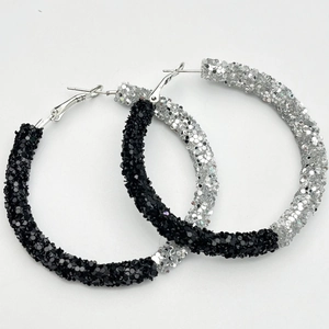 Close-up of oversized hoop earrings featuring sparkling black and silver glitter texture