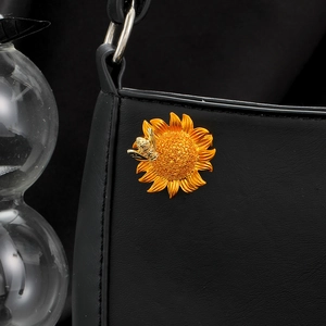 Detail of a golden sunflower brooch with a bee pinned on a black leather bag