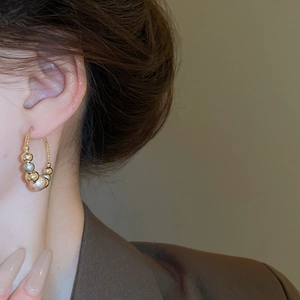 Close-up of mixed metal beaded hoop earrings with gold and silver spheres on a model