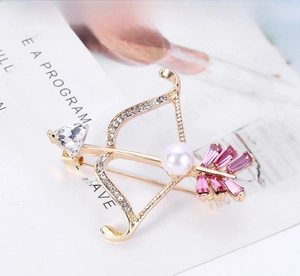 Close-up of Cupid's arrow brooch with pink crystals, pearl and gold rhinestones