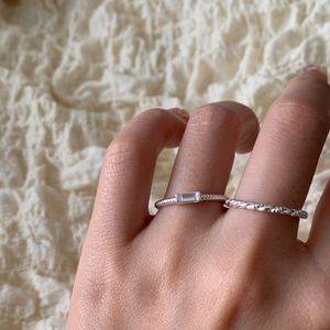 Detail of s925 silver twist band and rectangular zircon rings worn on female hand