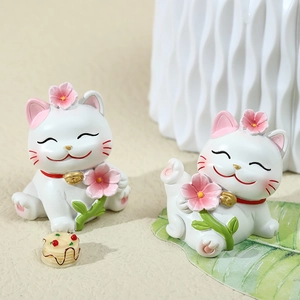 Cute cherry blossom lucky cat figurines set in resin with cake accessory on tabletop