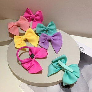 Detail of colorful bow hair clips and ties in vibrant macaron shades on a stone tray