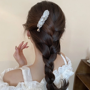 Elegant pearl shell hair clip on woman's braided hair with a French minimalist style
