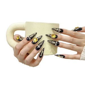 Handmade black stiletto press-on nails with yellow zircon crystals and gold foil accents
