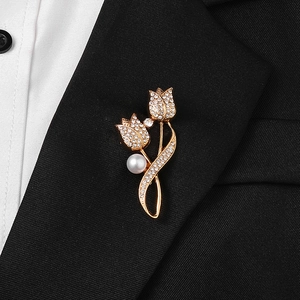 Elegant gold tulip brooch with rhinestones and white pearl on black blazer lapel