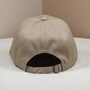 Detail of khaki cotton baseball cap showing adjustable bronze metal buckle and strap