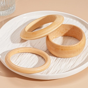 Detailed view of three vintage-style wooden bangles in various shapes on a ceramic plate