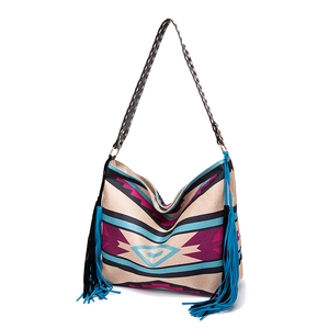 Detail of bohemian woven shoulder bag featuring colorful geometric patterns and long tassels