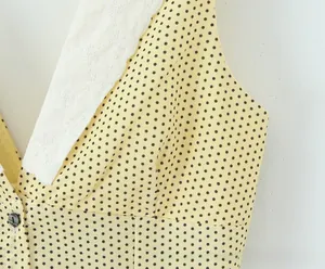 Detail of yellow polka dot dress with white lace V-neckline and decorative button