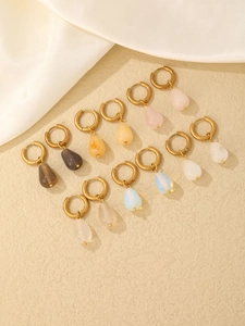 Close-up of teardrop natural stone hoop earrings in assorted colors on beige background