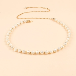Detail of gold metal chain waist belt with woven faux pearls and shell-shaped charms
