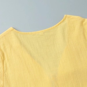 Close-up of V-neckline detail on a yellow linen blend skirt set with fine stitching