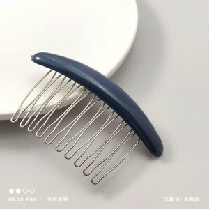 Detail of blue non-slip hair comb with metal teeth and plastic handle on a plate
