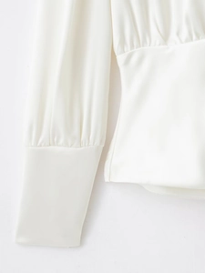 Détail de chemise en satin blanc avec poignets ajustés et texture de tissu lisse et brillant