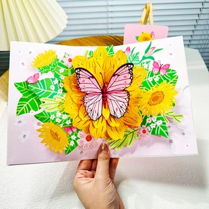 Handheld 3D pop-up greeting card featuring a pink butterfly on yellow sunflowers