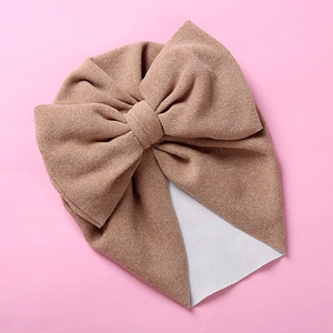 Detailed macro view of camel knitted baby turban hat with a large decorative bow