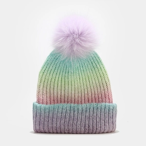 Détail de la maille tricotée d'un bonnet d'hiver dégradé avec un grand pompon violet