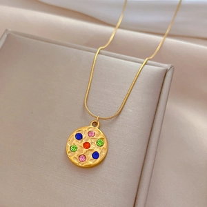 Detailed shot of a gold round pendant with colorful zircons on a snake chain necklace