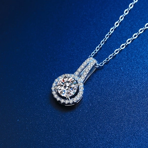 Elegant 2 carat halo round cut moissanite pendant necklace on a textured blue background