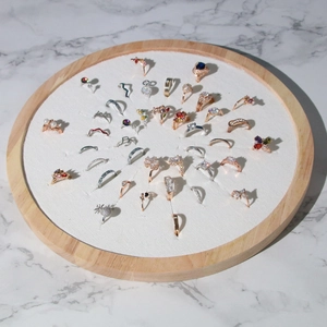 Detail view of various rings displayed on white velvet within a natural wooden jewelry tray