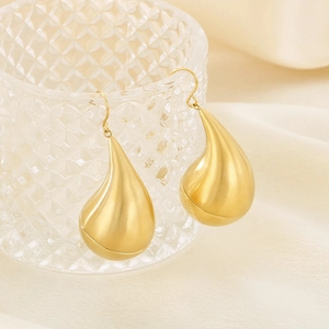 Macro detail of chunky gold teardrop earrings with matte finish on glass edge