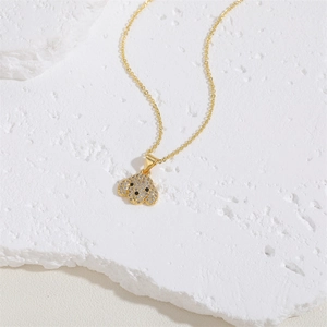 Macro view of a gold puppy pendant necklace with micro-pave zircons on textured stone