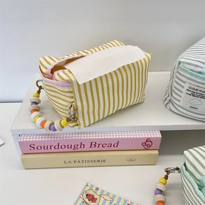 Macro detail of a yellow striped fabric tissue bag with colorful wooden bead handle
