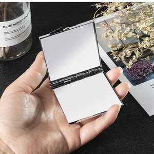 Close-up of open square silver foldable makeup mirror showing double-sided reflection