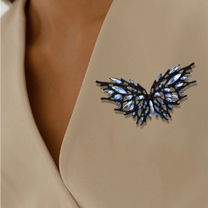 Dark style butterfly brooch with blue crystals on beige blazer lapel, elegant suit accessory