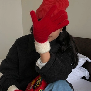 Detalle del gorro de punto rojo y guantes a juego con ribete de piel sintética blanca