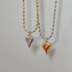 Détail de pendentifs cœur 3D polis miroir bicolores sur fines chaînes à perles or et argent