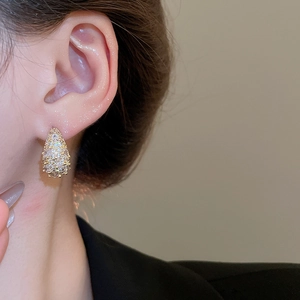 Close-up of gold drop earrings with paved zircons on model for elegant styling