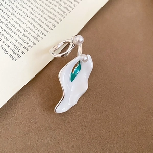 Detail of calla lily earring set with white petals and green stamens on book pages