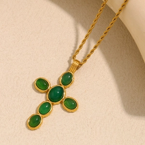 Close-up of a vintage 18K gold-plated cross necklace with five green emerald stones