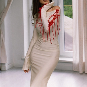 Detailed close-up of cream white dress featuring red lace-up ribbons on sleeves and chest