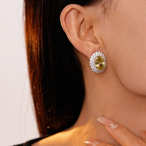 Close-up of small vintage silver stud earrings with oval yellow zircon and white stones