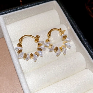 Macro detail of 18k gold-plated hoop earrings featuring inlaid irregular crystal stones
