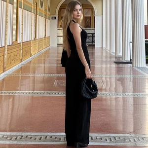 Detail of elegant black halter dress with matching woven handbag in a classic colonnade