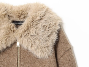 Dettaglio del collo in finta pelliccia beige e cerniera dorata su maglione di lana marrone
