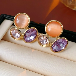 Macro shot of vintage style earrings with orange cat-eye stone and colorful crystals